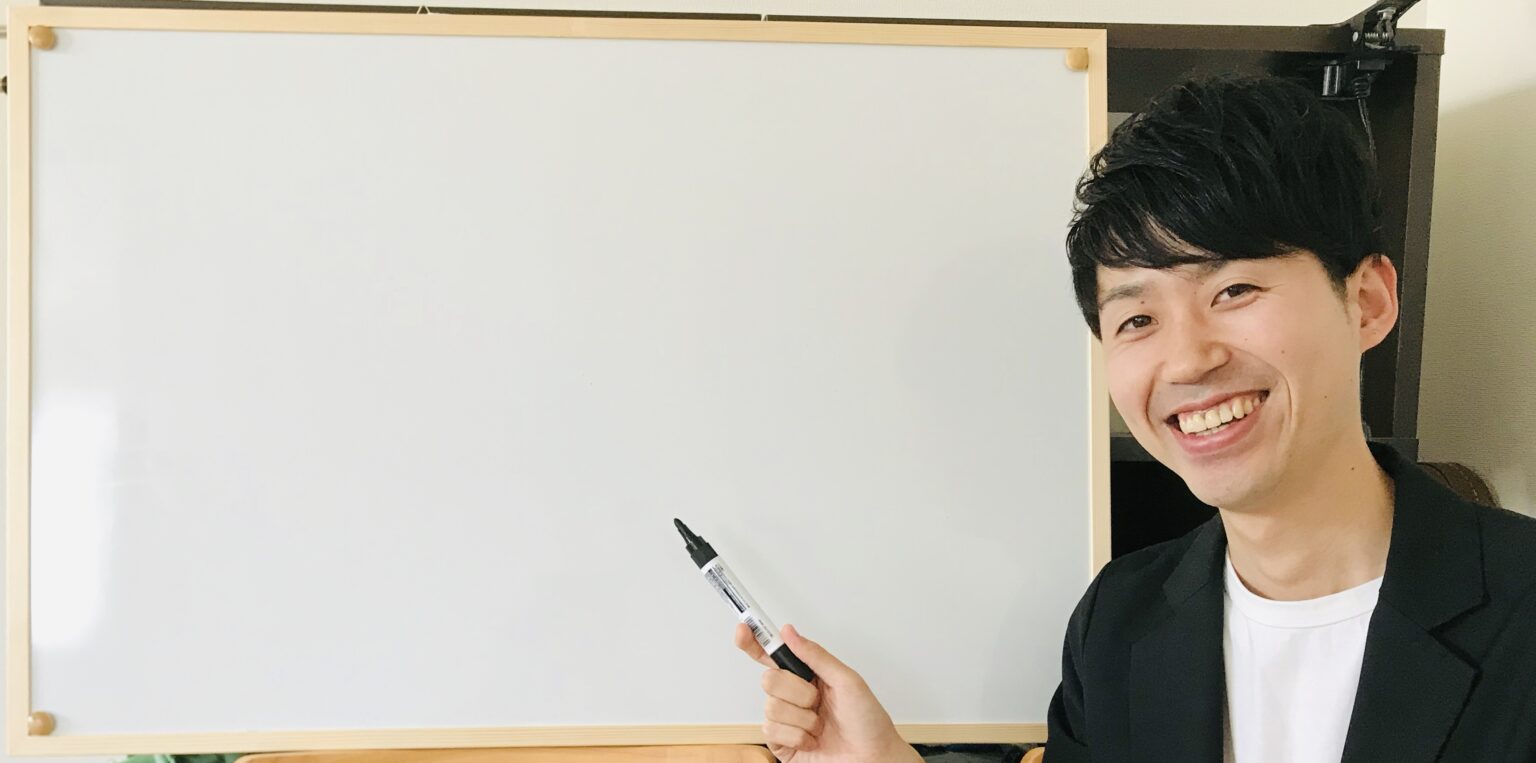 ホワイトボードの前で笑顔の講師・稲葉拓也